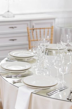 Beyaz seramik sofra takımı ve restoran arka planında cam eşyalar ile servis edilen ziyafet masası.