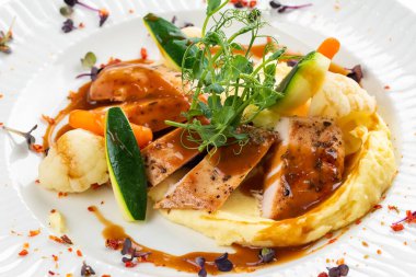 Izgara tavuk fileto dilimleri patates püresi ve yeşil soslu beyaz tabakta. 