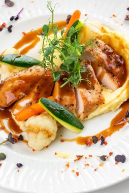 Izgara tavuk fileto dilimleri patates püresi ve yeşil soslu beyaz tabakta. 