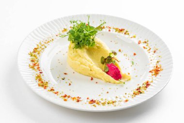 Tereyağlı patates püresi ve beyaz tabakta yeşil yaban turpu sosu. 