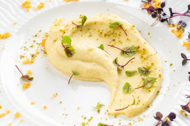 Beyaz tabakta tereyağlı ve yeşillikli yumuşak kremalı patates püresi 