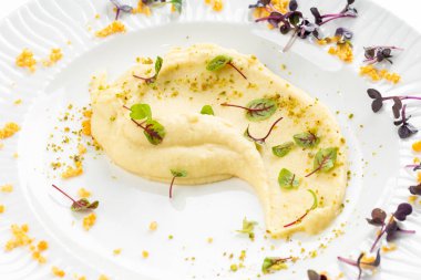 Beyaz tabakta tereyağlı ve yeşillikli yumuşak kremalı patates püresi 