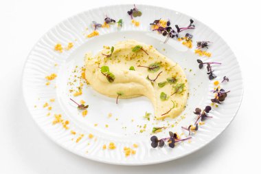 Beyaz tabakta tereyağlı ve yeşillikli yumuşak kremalı patates püresi 