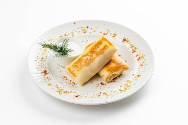 Lezzetli kızarmış Rus krepleri, altın hamurlu ve beyaz ekşi krema kasesi, kırsal masa arka planında.