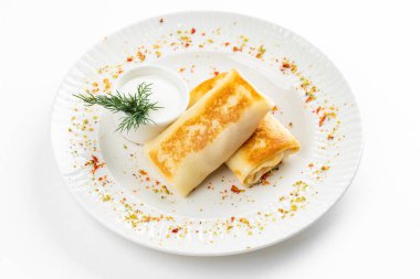 Lezzetli kızarmış Rus krepleri, altın hamurlu ve beyaz ekşi krema kasesi, kırsal masa arka planında.