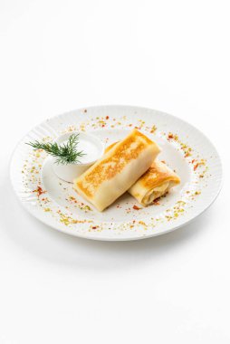 Lezzetli kızarmış Rus krepleri, altın hamurlu ve beyaz ekşi krema kasesi, kırsal masa arka planında.