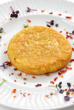 Kızarmış patates pirzolası, altın kabuklu ve beyaz tabakta otlar. 