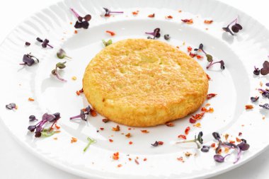 Kızarmış patates pirzolası, altın kabuklu ve beyaz tabakta otlar. 