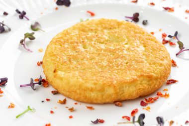 Kızarmış patates pirzolası, altın kabuklu ve beyaz tabakta otlar. 