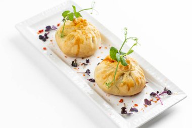 Domatesli fırınlanmış çörekler ve beyaz tabakta yeşillikle süslenmiş peynir. 