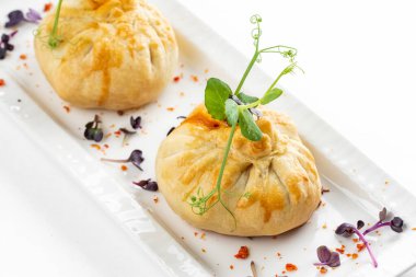 Domatesli fırınlanmış çörekler ve beyaz tabakta yeşillikle süslenmiş peynir. 