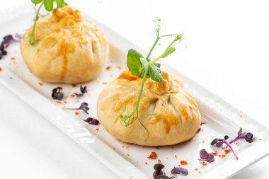 Domatesli fırınlanmış çörekler ve beyaz tabakta yeşillikle süslenmiş peynir. 