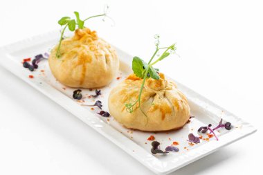 Domatesli fırınlanmış çörekler ve beyaz tabakta yeşillikle süslenmiş peynir. 