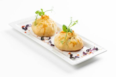 Domatesli fırınlanmış çörekler ve beyaz tabakta yeşillikle süslenmiş peynir. 