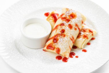 Rus krepleri altın hamurlu ve beyaz ekşi krema kasesi ve ahududu reçeli köy masasında.