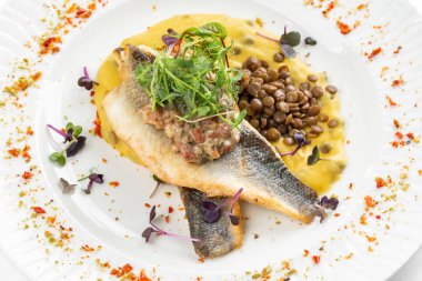 Patates püresi ve krema soslu balık filetosu otlar ve beyaz tabakta fasulye ile süslenmiş. 