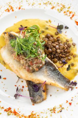 Patates püresi ve krema soslu balık filetosu otlar ve beyaz tabakta fasulye ile süslenmiş. 