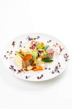 Patates püresi, sebze ve beyaz tabakta kırmızı soslu et madalyonları. 