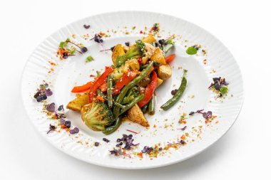 Kızarmış patates ve kırmızı biber dilimli yeşil fasulye. Beyaz tabakta sos. 