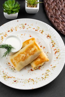 Rus krepleri altın hamurlu ve beyaz ekşi krema kasesi kırsal masa arkasında.