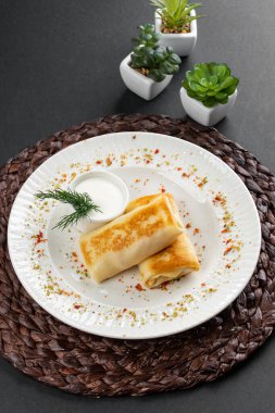 Rus krepleri altın hamurlu ve beyaz ekşi krema kasesi kırsal masa arkasında.