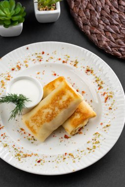 Rus krepleri altın hamurlu ve beyaz ekşi krema kasesi kırsal masa arkasında.