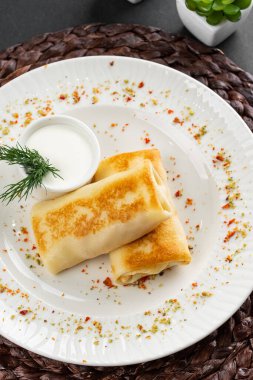 Rus krepleri altın hamurlu ve beyaz ekşi krema kasesi kırsal masa arkasında.