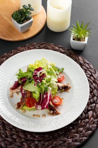 Renkli lezzetli salata, fırında somon, yeşillik ve domatesler kırsal ahşap peçetede beyaz tabakta. 