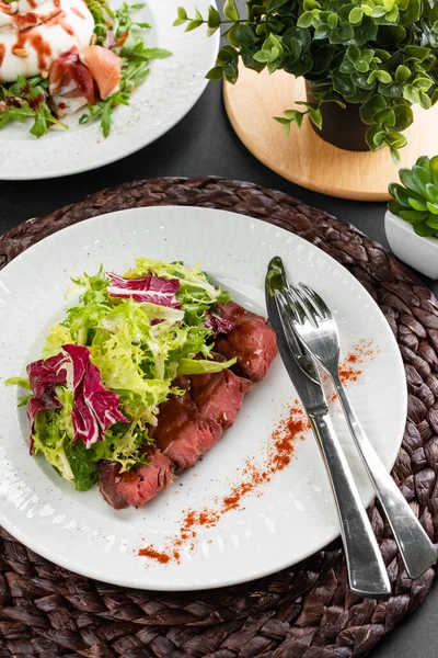 sığır eti dilimli renkli salata, yeşiller ve kırsal peçetede beyaz tabakta kırmızı biber.