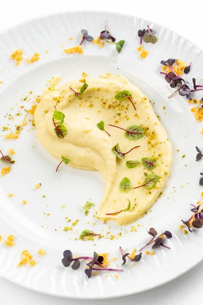 Beyaz tabakta tereyağlı ve yeşillikli yumuşak kremalı patates püresi 