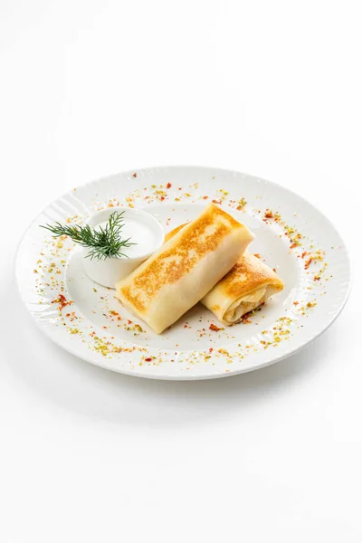 おいしい揚げは素朴なテーブルの背景に黄金の地殻と白いサワークリームボウルとロシアのパンケーキをロール — ストック写真