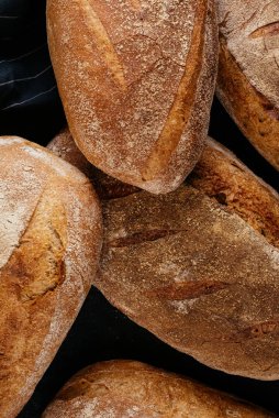 Siyah masa arkasında bir sürü taze pişmiş ekmek.