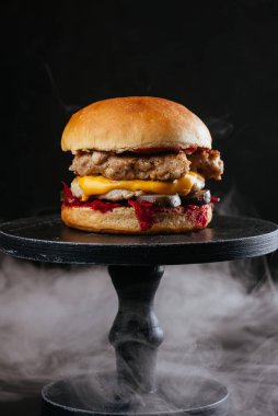 Lezzetli bbq cheeseburger ile et pirzolası, mantar ve siyah masa arkasında beyaz pişmiş çörekler.
