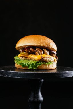 Köfteli köfte, ızgara mantar, peynir, taze salata yaprağı ve siyah ahşap masa arkaplanındaki sos.