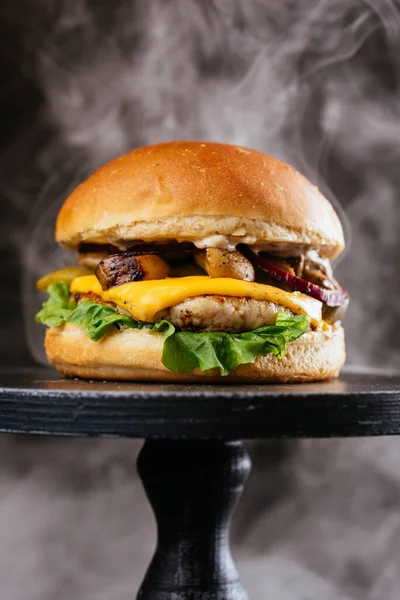 meat burger with white golden buns, grilled mushrooms, cheese, fresh salad leaf and sauce on black wooden table background