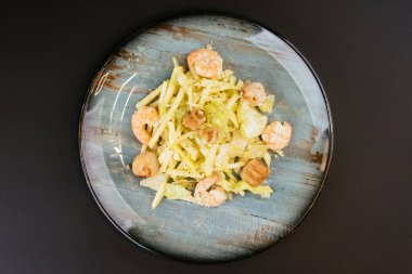 Siyah arka planda gri tabakta karidesli kızarmış patates.