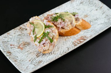 Beyaz tabakta tereyağı, balık ve limon parçaları.