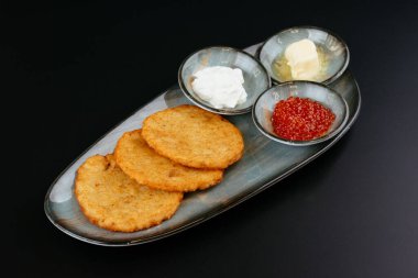 Siyah arka planda mavi tabakta soslu patates tortillası.