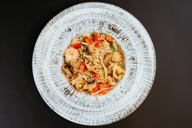 Marullu Asya eriştesi, kızarmış sebze ve domatesler masada.