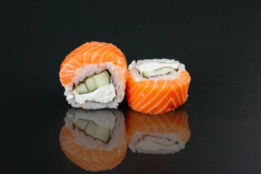 Balıklı suşi ve siyah masa arkasında krem peynirli beyaz pirinç.