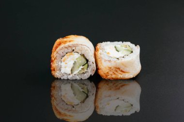 Balıklı suşi ve siyah masa arkasında krem peynirli beyaz pirinç.