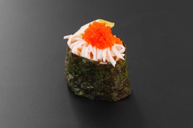 Somonlu suşi ve siyah arka planda avokado.