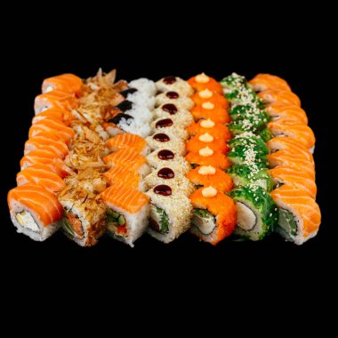 Kırmızı somon balığı, beyaz pirinç ve siyah arka planda izole edilmiş krem peynirli bir sürü farklı suşi rulosu.