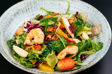 Mavi tabakta karides, yeşil ve domatesli renkli salata.