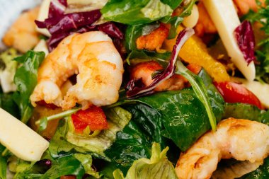 Mavi tabakta karides, yeşil ve domatesli renkli salata.