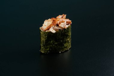 Somonlu suşi ve siyah arka planda avokado.