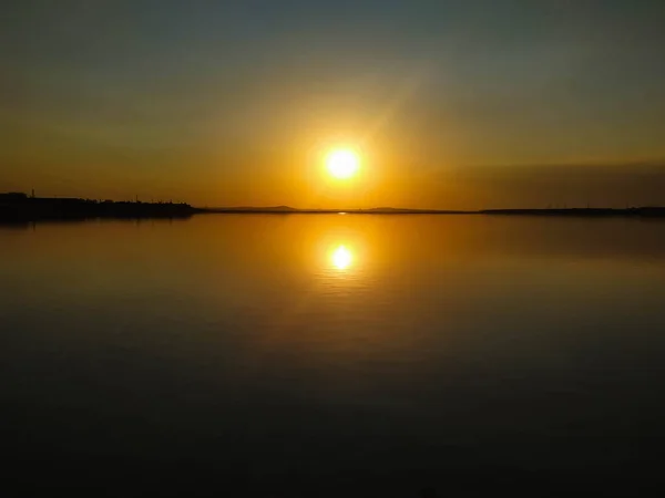 Sol refletindo sobre a água. Vista do pôr-do-sol. Pôr do sol na cidade . — Fotografia de Stock