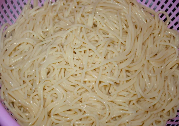 Pembe süzgeçli spagettiye yakın plan. Spagetti yapmak.