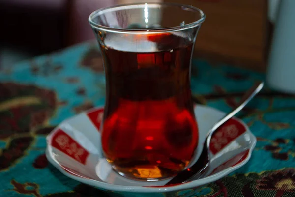 Üzerinde küçük bir kaşık olan çay bardağının üstünde mavi bir masa örtüsü ve hayvanlarla dolu bir çay bardağı. Azerbaycan 'da kullanılan armut şeklindeki cam, aynı zamanda armut camı olarak da bilinir..  