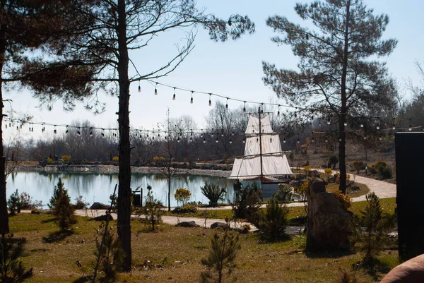 在一个有船帆的小湖上 白天的景色 湖水被树木环绕 挂在树上的轻盈的花环 图库图片